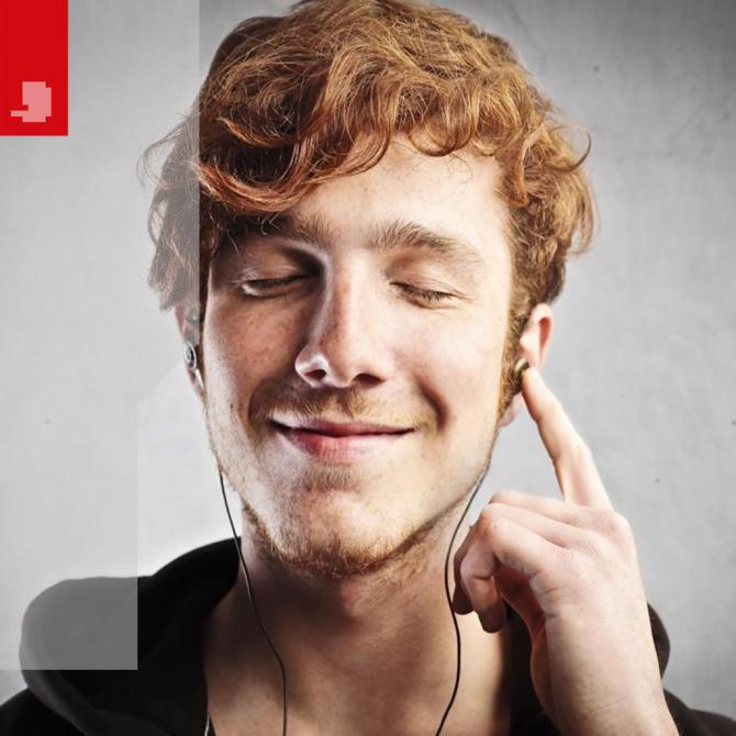 red haired man smiling while listening to music